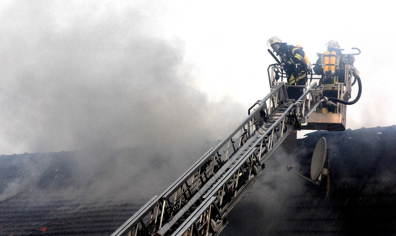 Feuerwehrmänner stehen auf der Leiter und löschen einen Dachstuhlbrand