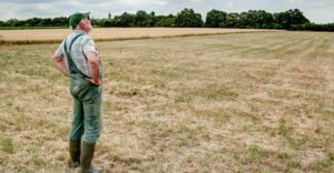 bauer steht vor seinem feld, schaut in den himmel und wartet auf regen