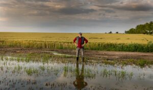 ein landwirt steht vor seinem überfluteten feld
